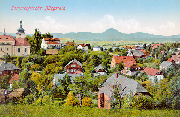 This picture postcard shows the central part of the village of Sloup with the houses below the church of St. Catherine. In teh background there is the Klíč hill.