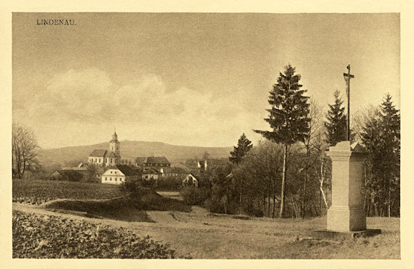 Diese Ansichtskarte zeigt das Ortszentrum mit der Kirche St. Peter u. Paul vom Südosten. Im Vordergrund sieht man das heute nicht mehr bestehende Niesigs Kreuz, an dem damals ein Feldweg nach Brniště (Brins) vorbeiführte.