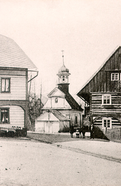 This picture postcard without a date shows the older chapel of the Assumption of Virgin Mary from 1725. This chapel stood originally on the road crossing in the lower part of the village and had been demolished in 1923.