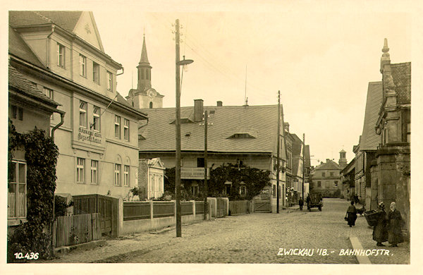 Auf dieser Ansichtskarte aus der zweiten Hälfte der 20er Jahre des 20. Jahrhunderts ist die frühere Bahnhofsstrasse, die vom Marktplatz nach Süden führte, abgebildet. Im Vordergrund sieht man das damalige „Bezirkshaus“, im Gebäude hinter ihm (in der Mitte des Bildes) war der Sitz der Sodawasser- und Essigfabrik Rössler, die unter anderem auch einen ausgezeichneten Senf produzierte.