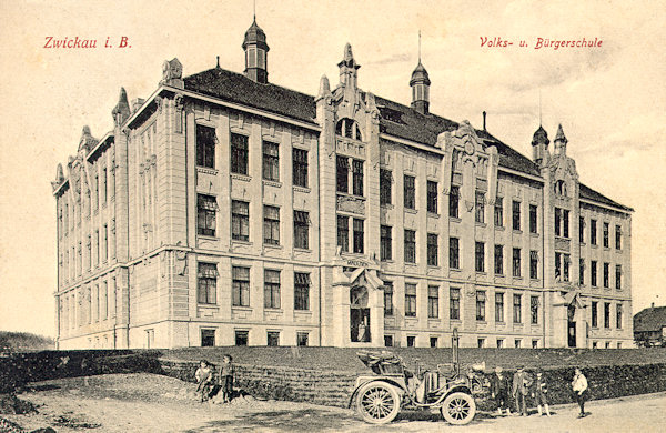 Auf dieser Ansichtskarte aus der Zeit vor dem 1. Weltkrieg sieht man das am Stadtparke 1906-1907 erbaute monumentale Gebäude der Volks- und Bürgerschule. Das vor der Schule stehende Automobil könnte dem damaligen Pfarrer Bensch gehören, der mit ihm zum Religionsunterricht in die Dörfer der Umgebung fuhr.