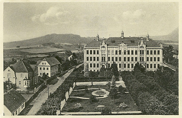 Diese Ansichtskarte zeigt die Volks- und Bürgerschule in Cvikov mit dem anliegenden Park im Blick vom Turm der St. Elisabethkirche. Links sieht man die Häuser in der Čechova ulice-Gasse, die heute unmittelbar neben der Schule von der neuen Umgehungsstrasse überquert wird.