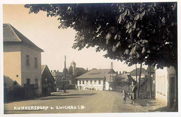 This picture postcard from between the wars shows the main road coming from Jablonné v Podještědí with the restaurant „Zur Post“ in the middle. In the background there is the church of Elevation of the Holy Cross.