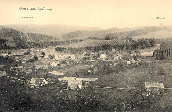 Diese Ansichtskarte zeigt den nördlichen Teil der Ortschaft im Blick vom Lesní vrch (Waldberg). Links hinter den Häusern ragt aus dem Walde der Křížová věž (Rabenstein) und rechts am Horizont sieht man den Felsen des Milštejn (Mühlstein).