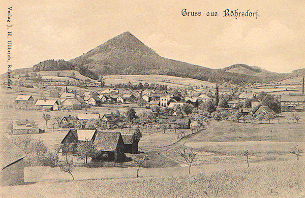 Auf dieser Ansichtskarte sieht man das ganze, malerisch unter dem markanten Kegelberge Klíč (Kleis) ausgebreitete Dorf liegen.