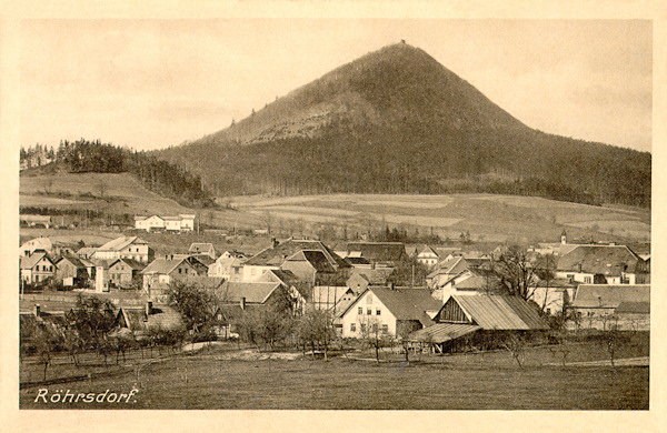 This picture postcard from 1915 records the lower part of Svor as seen approximately from the East. Over the village the railwas-station is shown, behind of which there are the lower peak of the Sokolík-hill and in the background the prominent cone of the Klíč on the peak of which the small cabin is clearly visible.