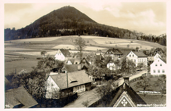 Diese Ansichtskarte zeigt den Blick von der Eisenbahnbrücke auf die Häuser im Oberdorf. Im Hintergrund erhebt sich der kegelförmige Klíč-Berg.