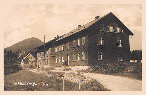 Tato pohlednice zachycuje dvojici obytných domů na severním okraji obce, jejichž vzhled se dodnes téměř nezměnil. V pozadí je hora Klíč.