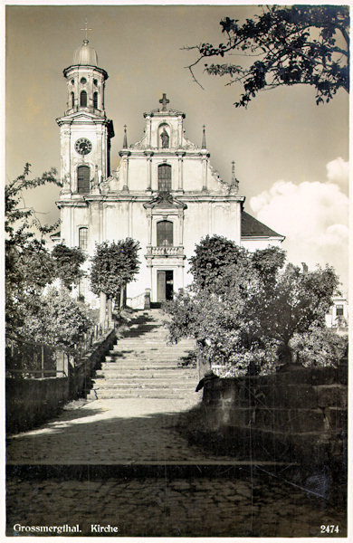 Diese Ansichtskarte aus der Zwischenkriegszeit zeigt die Stirnwand der Kirche St. Maria Magdalena, die in den 80er Jahren des 20. Jahrhundert zum Abriss bestimmt war. Die Kirche wurde nur durch die Bemühungen Marcel Hrubý´s und die uneigennützige Hilfe vieler anderer Enthusiasten gerettet.