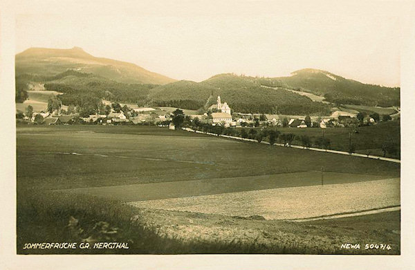 This picture postcard shows the centre of Mařenice with the church of St Mary Magdalene seen from the west. The road in the foreground leads to Cvikov, behind the village rises the Zámecký vrch (Castle hill) and on the left side in the background is on the border between Bohemia and Saxonia rises the Hvozd.