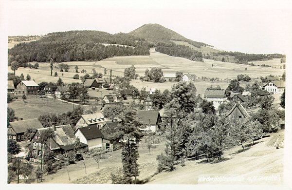 Auf dieser Ansichtkarte aus der Zeit vor dem 2. Weltkrieg sieht man das Ortszentrum mit dem Berge Luž (Lausche) im Hintergrund. Ganz rechts ist deutlich das ehemalige Hotel Adler und etwas näher links von ihm das frühere Hotel Schäfer zu sehen.