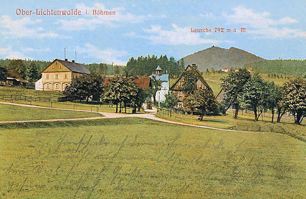 Diese Ansichtskarte zeigt das Ortszentrum mit der Kapelle, die nach dem 2. Weltkrieg abgerissen wurde. Im Hintergrund ragt der Luž-Berg (Lausche) mit dem Bergrestaurant auf dem Gipfel empor.