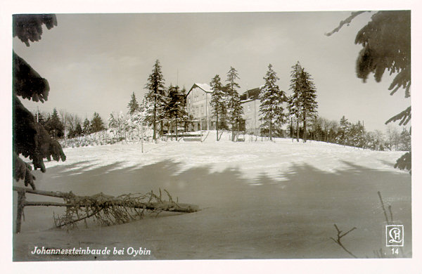 Diese Winter-Ansichtskarte aus der Zeit um 1935 zeigt die Gaststätte auf den Johannissteinen (Janské kameny) vom Südwesten. Hinter den Bäumen links sieht man den Basaltfelsen mit der Aussichtsplattform.