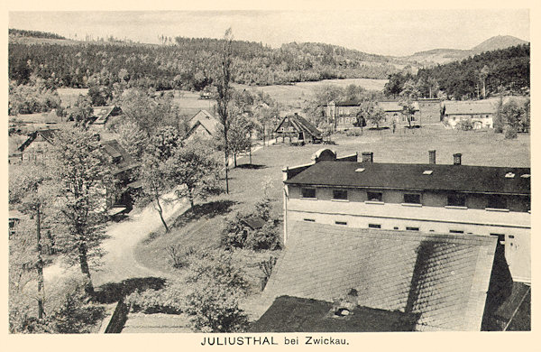 On this picture postcard the village Juliovka as seen from the southeast is shown. The building of the weawing mill in 1944 had been destroyed by flames and at present there remain only small rests of the foundations hidden under shrubs at the former playground. In the background the group of houses on the cross-road is shown, from which the former Knobloch's restaurant with a great dance hall is apparent. On the horizon on the right side there is the Luž-hill.
