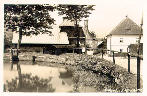 Auf dieser Ansichtskarte sieht man die ehemalige Schule, das ihr gegenüberliegende Haus und die Kirche der Vierzehn hl. Nothelfer im Blick vom kleinen Teich neben dem Schloss.