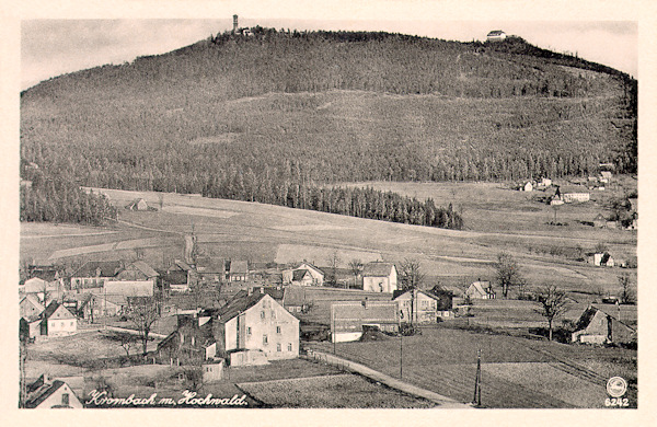 Diese Ansichtskarte aus der Zeit vor dem 2. Weltkrieg zeigt den oberen Teil von Valy (Schanzendorf) mit dem Gebäude des Gasthauses „Am Kammweg“ im Vordergrund. Der Horizont wird vom zweigipfeligen Berg Hvozd (Hochwald) mit seinem gut sichtbaren Aussichtsturm und der deutschen Baude eingenommen.