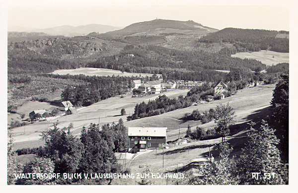 This picture postcard shows the landscape on the state border between the hill Luž and the Hvozd hill with its look-out tower in the background. In the centre the group of houses at the border crossing Wache between Dolní Světlá and Waltersdorf in Germany is seen.