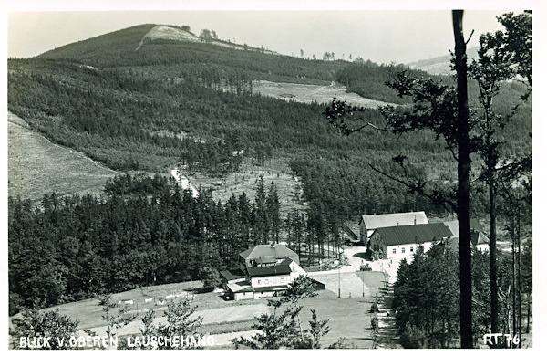 This picture postcard shows the border crossing at the „Wache“ over Dolní Světlá as seen from the slope of the Luž hill. On the right side there are the buildings of the at present already demolished hotel „Zur deutschen Wacht“ standing on the Bohemian side of the border, and on the left there is the still standing German hotel „Rübezahl“. In the background there is the Sonnenberg hill (in Germany).
