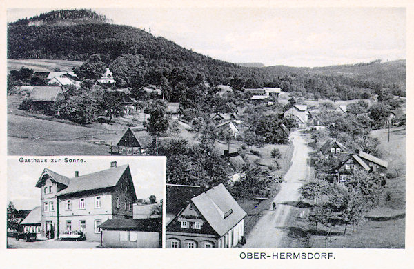 Auf dieser Ansichtskarte sieht man die Häuser im oberen Teil der Gemeinde an der Strasse nach Krompach (Krombach). Im Ausschnitt unten ist die im Jahr 1873 gegründete Gaststätte „Zur Sonne“, die bis Kriegsende im Besitz der Familie Heinrich war. Links über der Gemeinde erhebt sich der Zámecký vrch (Schlossberg).