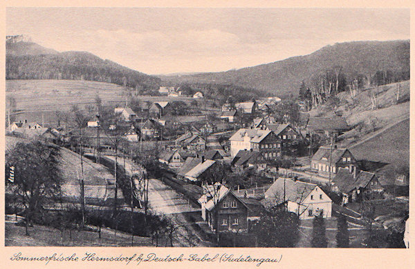 This picture postcard from World War Two shows the upper part of Heřmanice village. In the foreground there is the road to Mařenice and to the right between the houses leads the road to Krompach built in the first years of the 20s of the 20th century. The great two-storeyed house in the centre served as restaurant and after the war it was used as a holiday-house.