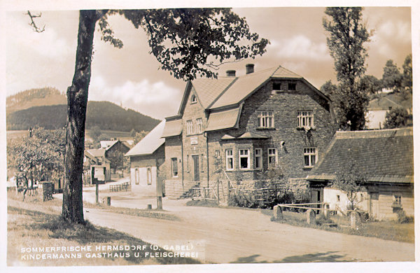 Na pohlednici z roku 1937 je bývalý Kindermannův hostinec s řeznictvím, jehož budova dodnes stojí u křižovatky v horní části vsi. V pozadí je Zámecký vrch.