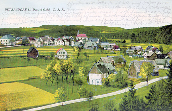 This picture postcard shows Petrovice with the church of the Holy Trinity as seen from the slopes of the Petrovický vrch-hill. In the centre there is the prominent church of St. Trinity, and on the extreme left the former schoolhouse. Along of the road in the foreground in present days ther is no one of the shown houses.