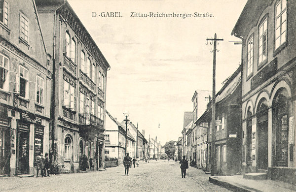 Diese Ansichtskarte zeigt die Zittau-Reichenberger Strasse ungefähr an der Stelle, an der früher das obere Stadttor stand. An der linken Seite blieb nur ein zur Unkenntlichkeit umgebautes grosses zweistöckiges Haus stehen, während sich die rechte Seite mit Ausnahme zweier Häuser im Vordergrund bis heute erhalten konnte.