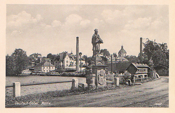 Auf dieser Ansichtskarte sieht man die schöne barocke Skulptur des hl. Johann von Nepomuk, die zusammen mit der daneben stehenden Statue der hl. Zdislava an der Brücke im Damm des Mlýnský rybník (Mühlteich) stand. Beide Statuen wurden später zum Dom des hl. Laurentius und der hl. Zdislava übertragen.