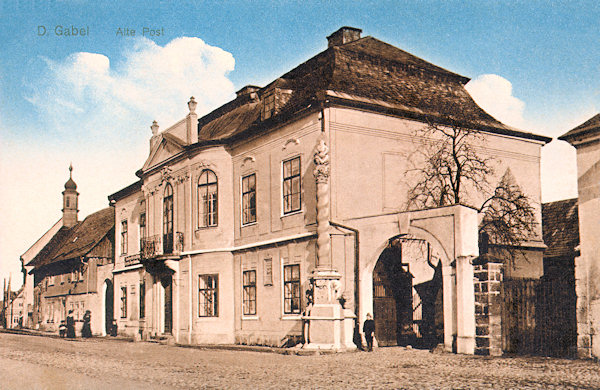 This picture postcard shows the rococo style manor house of Pachta von Rájov with the baroque corner column with the sculpture of the Holy Trinity.