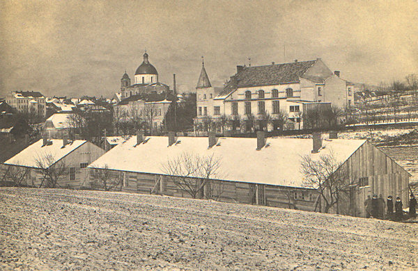 On this picture postcard we see the building of the firing range with the Dome of St. Lawrence and St. Zdislava in the background. The wooden barracks in the foreground belonged to the detention camp near of the village Lada and served for the accomodation of officers.