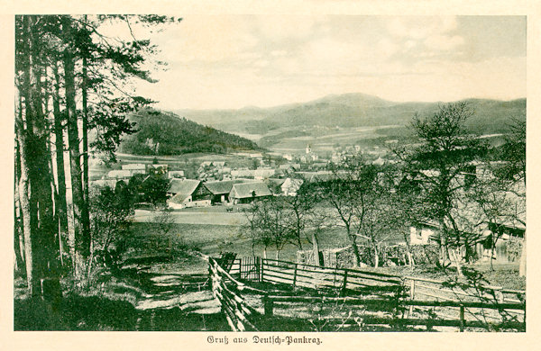 Auf dieser Ansichtskarte aus den Jahren um 1930 sieht man die ganze Gemeinde gesehen von ihrem oberen Ende am Hange des Velký Vápenný-Berges (Grosser Kalkberg). Links hinter den Bäumen ragt der Kostelní vrch (Kirchberg) empor, den Horizont schliesst der langgestreckte Kamm des Hvozd (Hochwald) ab.