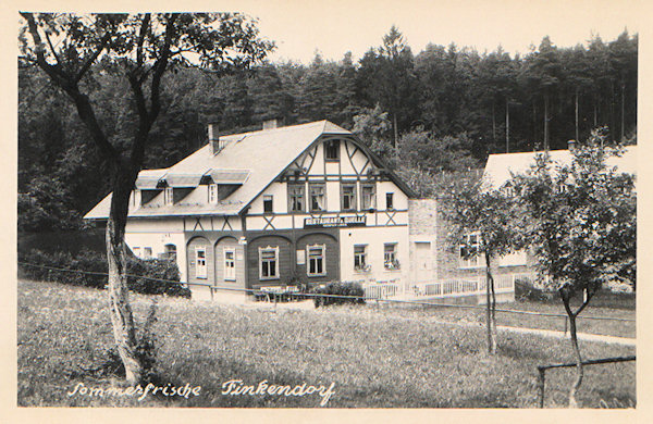 Auf dieser Ansichtskarte sieht man das ehemalige, nicht weit vom Teich in der Ortsmitte stehende Gasthaus „Zur Quelle“. Das Haus hat sich bis heute sein Aussehen erhalten und heute befindet sich in ihm die Pension „U Budulínka“.