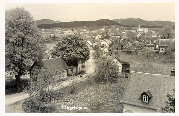 Na této pohlednici vidíme Rynoltice s výraznou budovou Schichtovy továrny na mýdlo. V popředí jsou domky u silnice do Janovic.