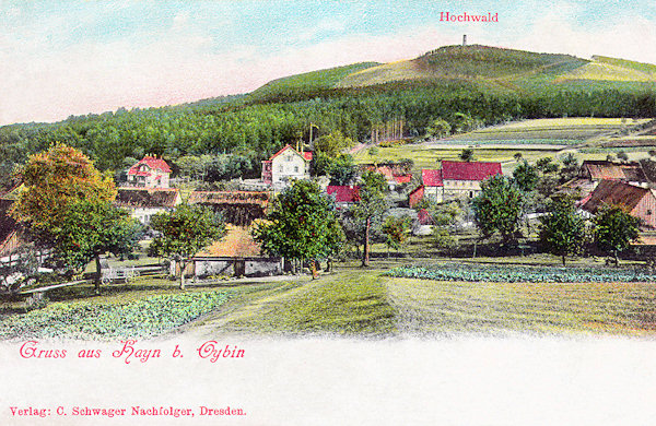 Diese Ansichtskarte zeigt den Blick auf die Gemeinde Hain vom Norden. Im Hintergrund ist der Gipfel des Hochwald (Hvozd) mit seinem Aussichtsturm.