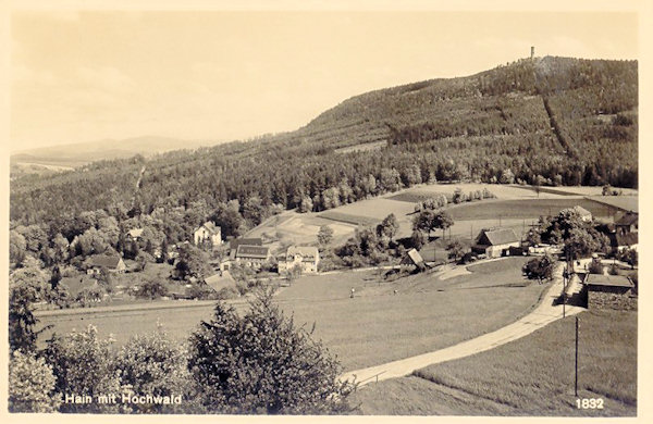 Diese Ansichtskarte zeigt die Gemeinde Hain im Jahre 1932. Im Vordergrund ist der aus dem Sattel zum Janské kameny (Johannisstein) führende Grenzweg, am Horizont der Hochwald (Hvozd) mit dem Aussichtsturm.