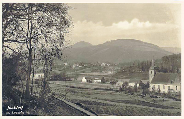 Diese Ansichtskarte von ca. 1930 zeigt einen Teil der Gemeinde mit der Kirche. Im Hintergrund der Buchberg und hinter ihm die Lausche (Luž).