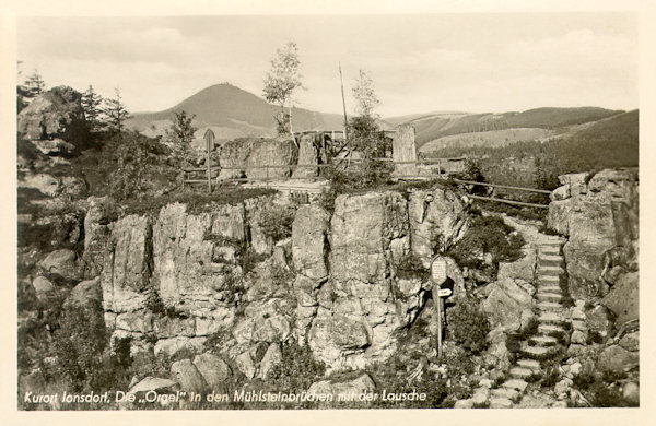 This picture postcard from the middle of the 20th century shows the outlook with the rocks of the Grosse und Kleine Orgel (Great and the Small organ) in the Millstone rocks of Jonsdorf. In the background rises the Luž-hill.