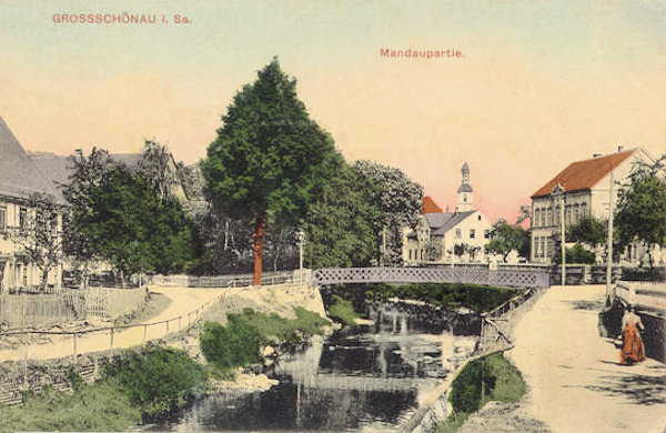 This postcard from 1911 shows the houses at the river Mandau with a bridge. In the background there is the tower of the church.