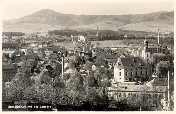 This postcard shows the central part of the village with the church. In the background there is the mountain range with the Luž.