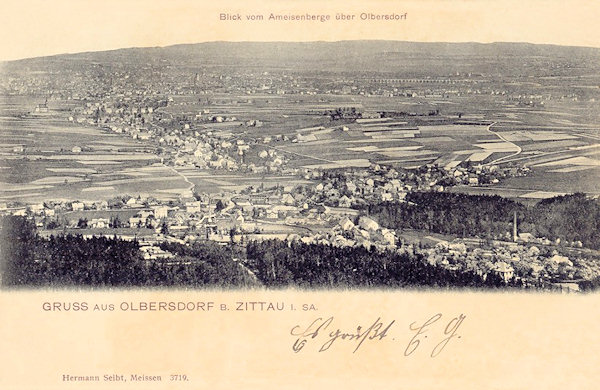 Diese Ansichtskarte von 1905 zeigt Olbersdorf vom Ameisenberg aus gesehen. Im Vordergrund ist das am Fusse der Berge liegende Oberdorf und im breiten Tal dahinter dehnt sich das Niederdorf mit der ehemaligen Kirche auf der Anhöhe (links). Im Hintergrund sieht man undeutlich Zittau und rechts davon den langen Viadukt der Bahnstrecke nach Liberec.