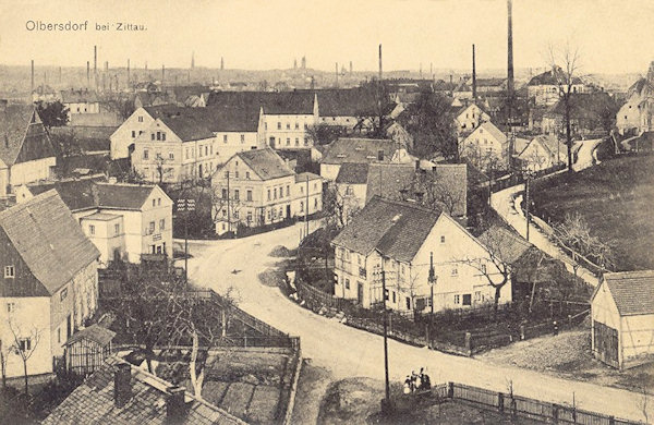 Diese Ansichtskarte von 1911 zeigt die an der Dorfstrasse im Niederdorf stehenden Häuser. Am Horizont sieht man die Schornsteine und Türme von Zittau.
