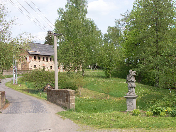 Die Straße nach Maxov (Maxdorf) mit einer Brücke und einer Statue des Heiligen Johannes von Nepomuk. Im Hintergrund ist das Gebäude des ehemaligen Hufnagel-Hofes zu sehen.