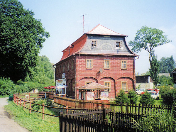 Mit Holz verkleidetes einstöckiges Haus mit geschmücktem Giebel und Mansardendach.