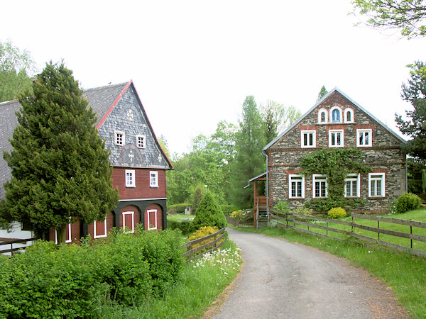 Der Backsteinbau der ehemaligen Mühle und das hölzerne Anwesen an der Straße, die aus dem Dorf nach Antonínovo údolí (Antoniental) führt.