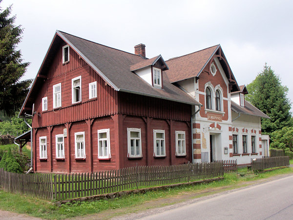 Typický poloroubený vesnický dům s podstávkou a dřevem obloženým štítem.