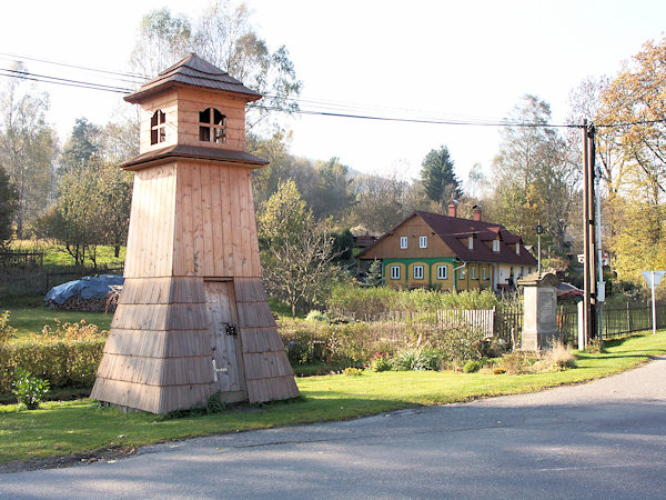 Neuzeitlicher, hölzerner Glockenturm in der Dorfmitte. Rechts davon steht das Palme-Kreuz.