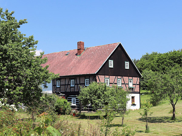 Ein großes Haus mit einem Holzzimmer und Fachwerk im Stock am nördlichen Ende des Dorfes.