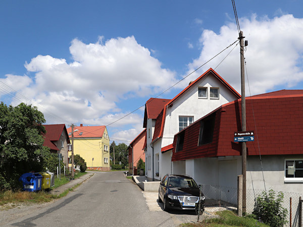 Domky u silnice v horní části vsi. Vpravo býval obchod a v pozadí je žlutá budova bývalé školy.