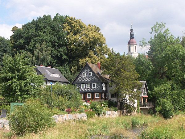 Häuser in der Nähe der Mandau im zentralen Teil des Dorfes. Im Hintergrund hebt sich der Kirchturm.