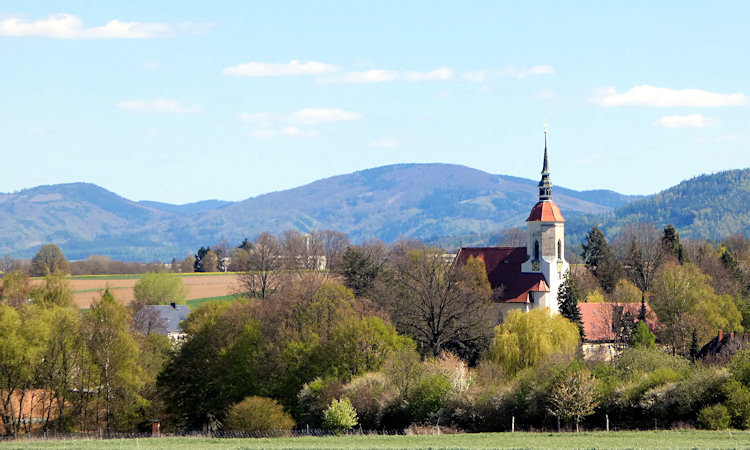 Blick über Bertsdorf mit der Dorfkirche vor den Bergen des Zittauer Gebirges.